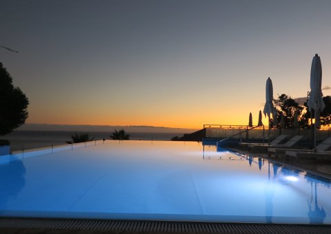 Wie harmonisch, der beleuchtete Pool des Hotels vor dem Sonnenuntergang über dem Horizont. 